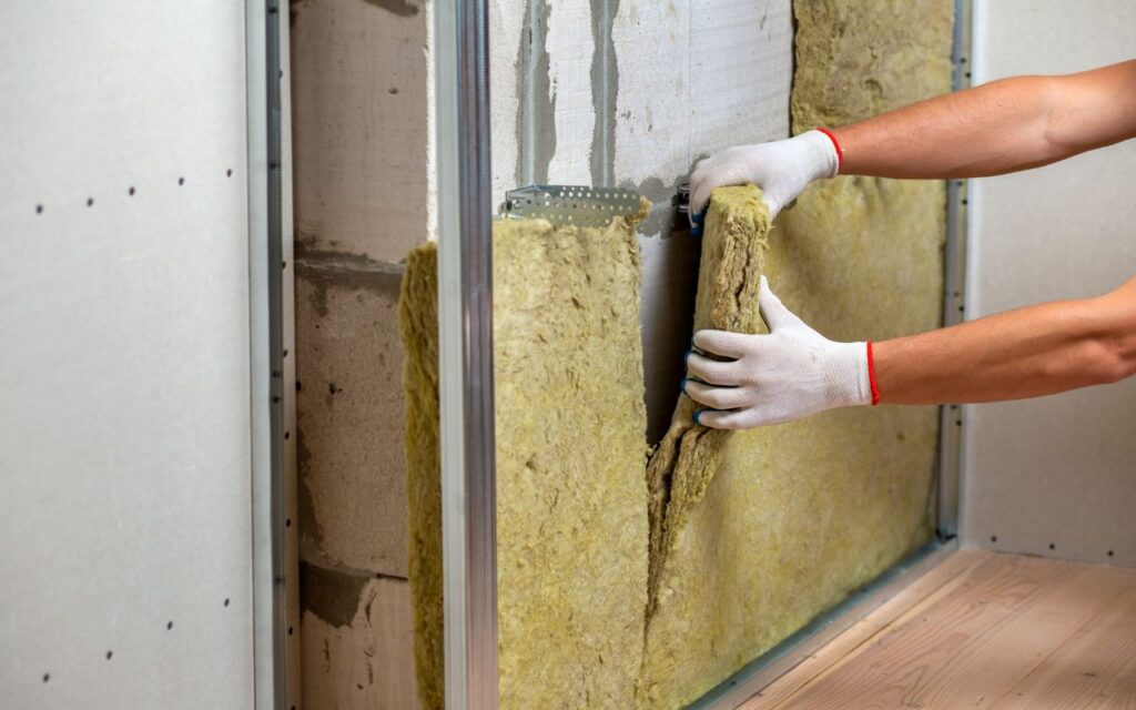 mężczyzna układający wełnę mineralną knauf